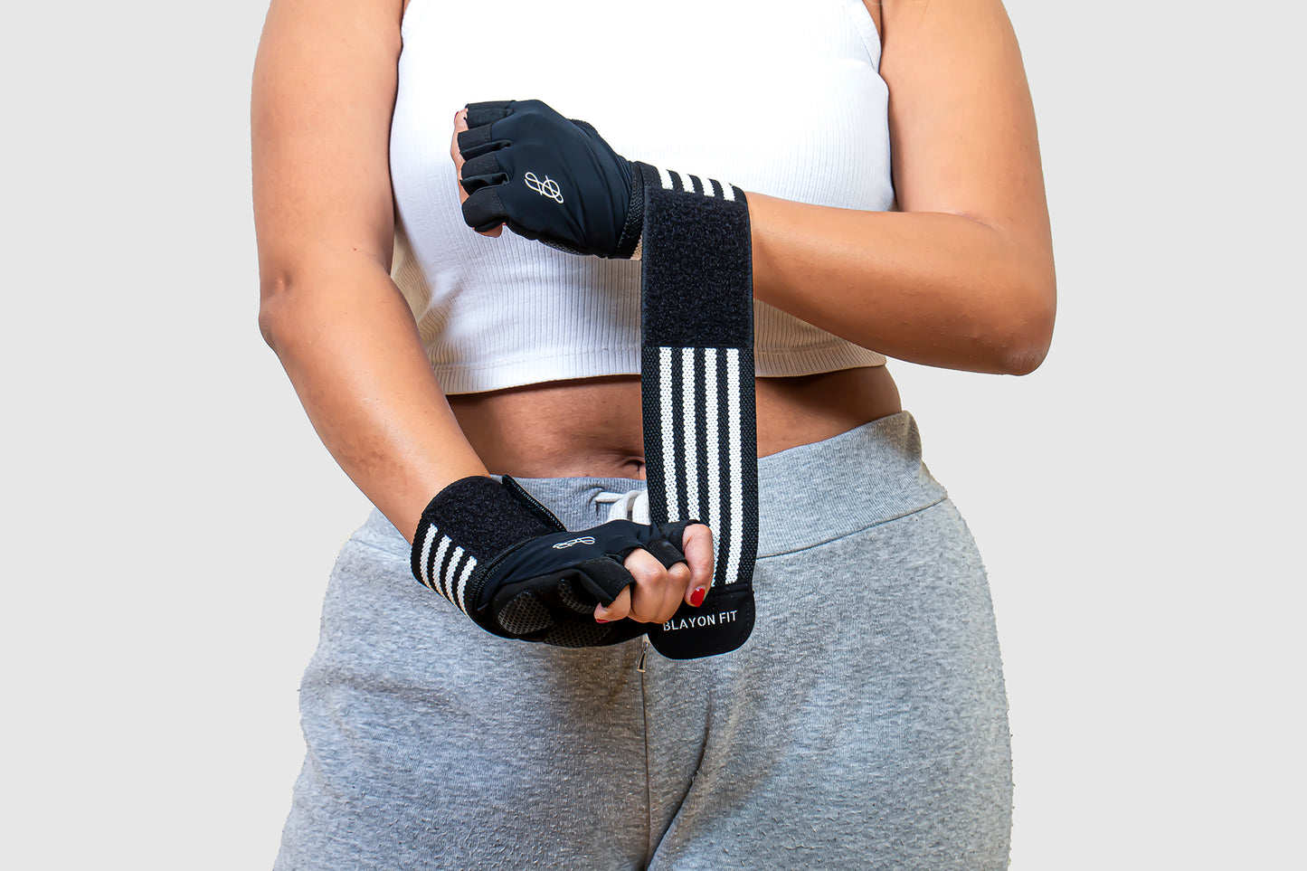 woman female wrapping the wrist support of the gym gloves around her wrist for a stable grip.